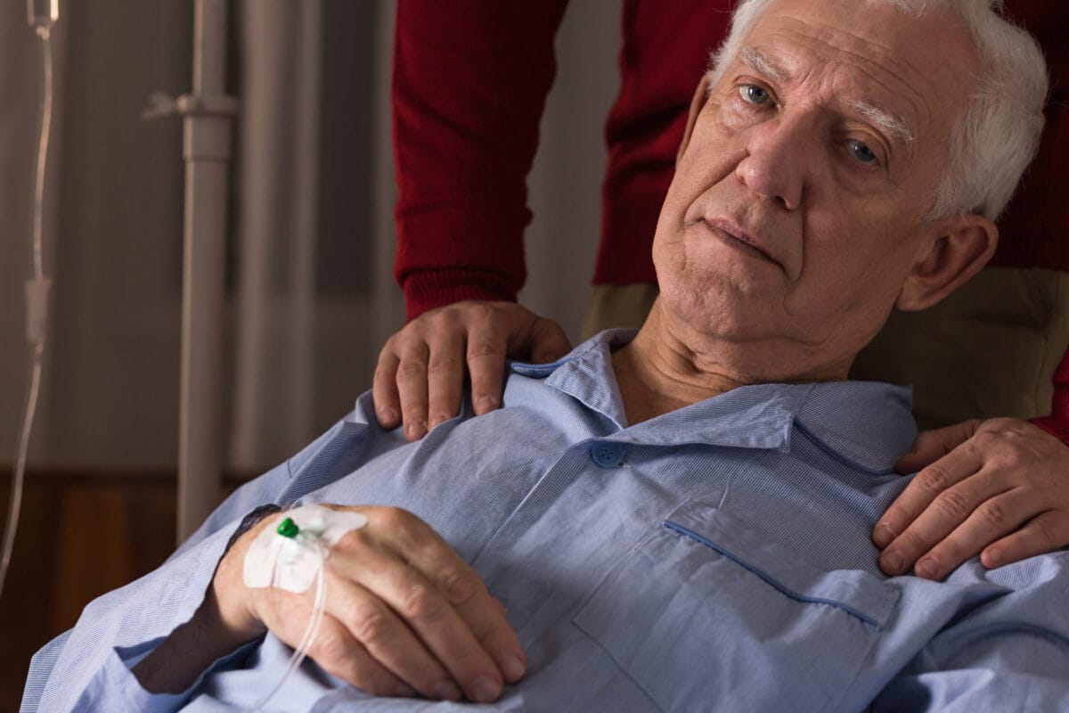 Homem idoso com uma sonda de soro na mão direita
